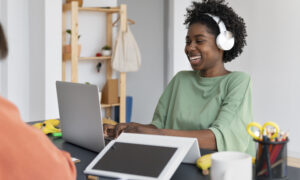 Women sitting at laptop wearing over the hear headphones