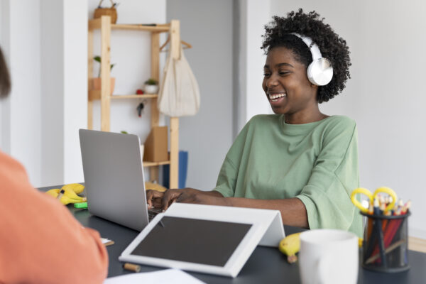 Women sitting at laptop wearing over the hear headphones