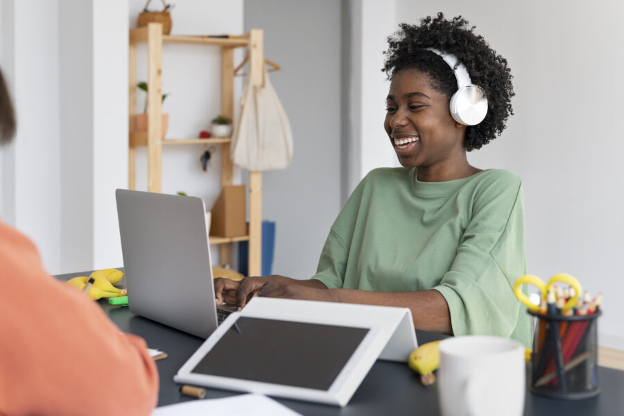 Women sitting at laptop wearing over the hear headphones