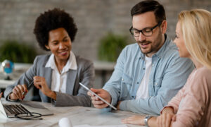 husband and wife meeting with bank manager, sitting at a table.