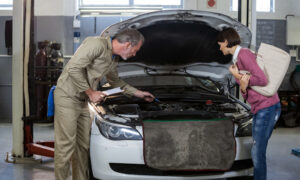 Man and women standing over an open car hood.