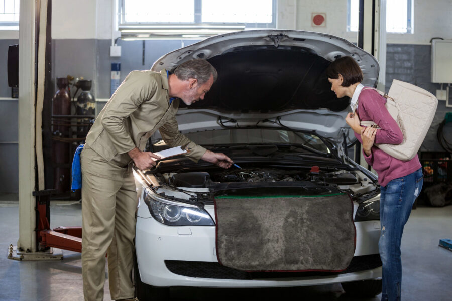Man and women standing over an open car hood.