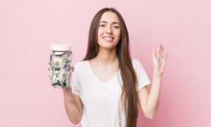 Women in v-neck t shirt smiling while holding a jar of money.