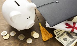 a piggy bank sitting next to a graduation cap on a table.