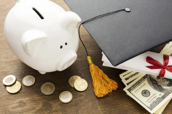 a piggy bank sitting next to a graduation cap on a table.