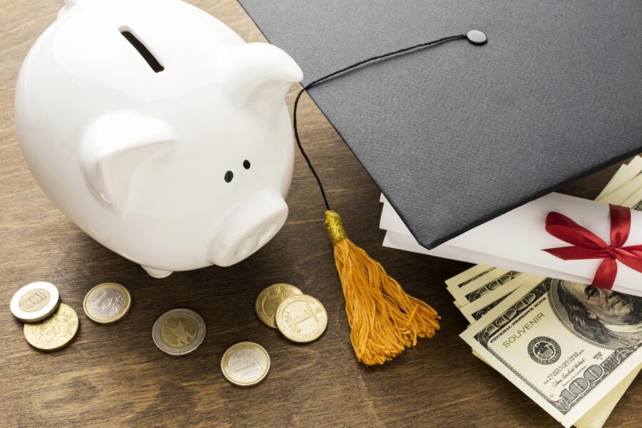 a piggy bank sitting next to a graduation cap on a table.