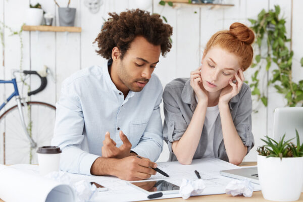A man and women sitting at a table together, paying bills and their debt