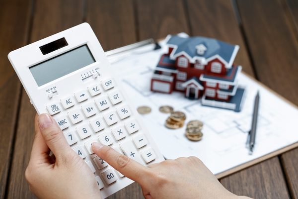 female-hand-operating-calculator-front-villa-house-model-scaled.jpg